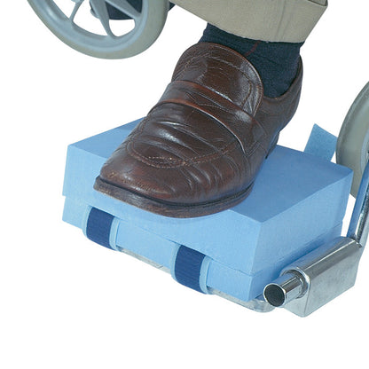 The AliMed Footrest Elevation Kit features a blue foam block elevating a foot in a brown shoe on a wheelchair footrest.