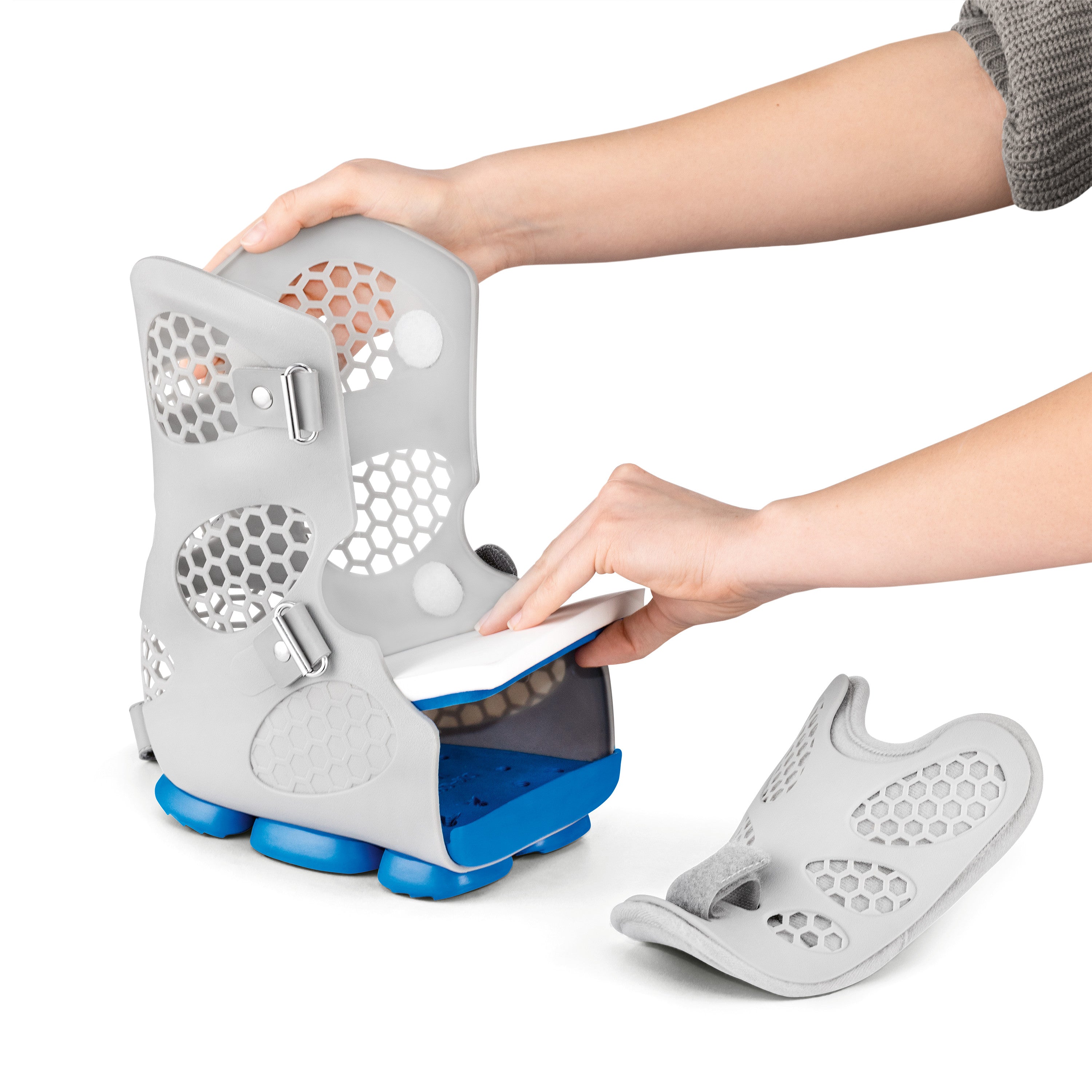 A person adjusts the DARCO Body Armor PFA Walker, featuring a gray, ventilated design with blue soles, inserting a white insole.