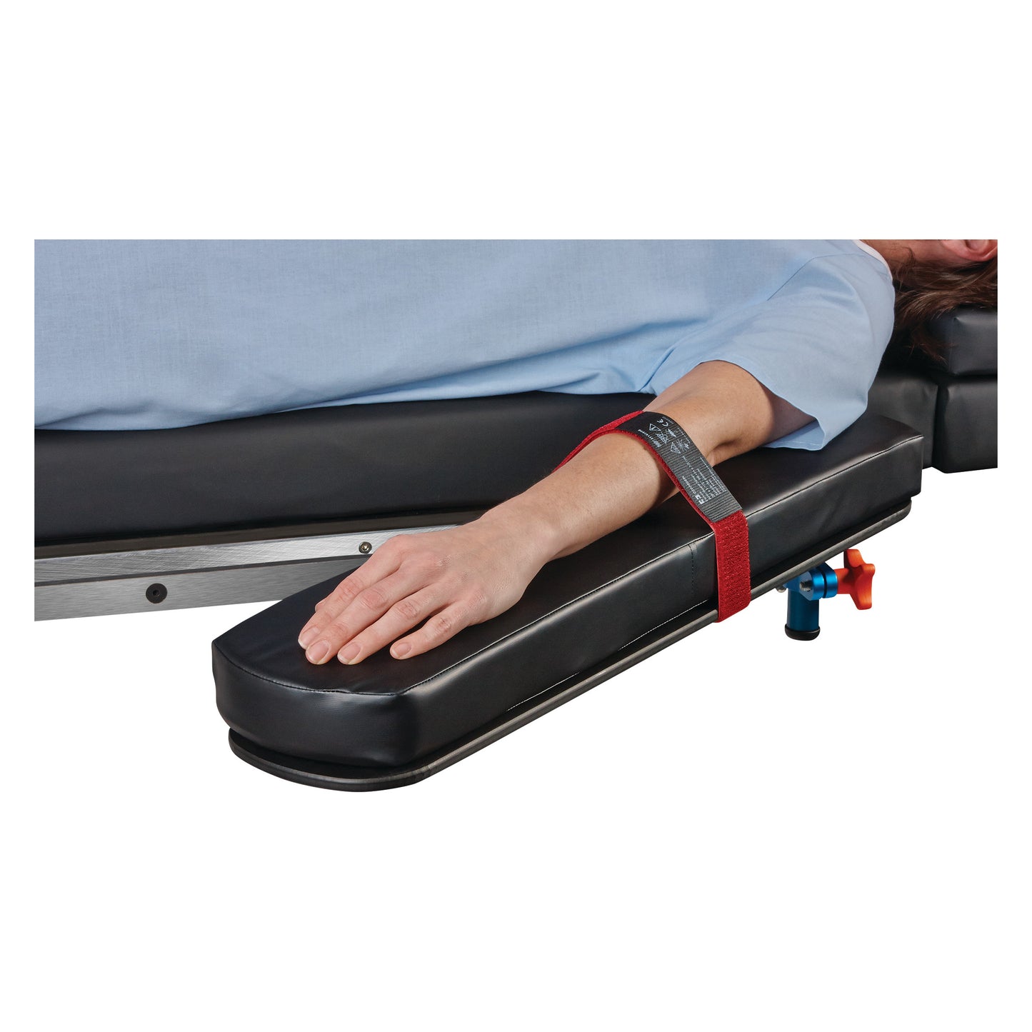 A person's arm is secured on a padded armboard with the Covidien Devon Reusable Armboard Strap in a medical setting.