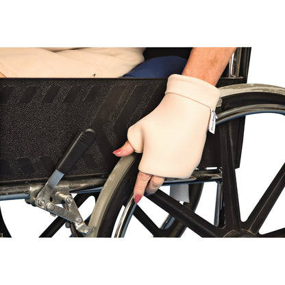 A hand wearing a DermaSaver Knuckle Protector rests on the wheel of a wheelchair next to a black textured panel.