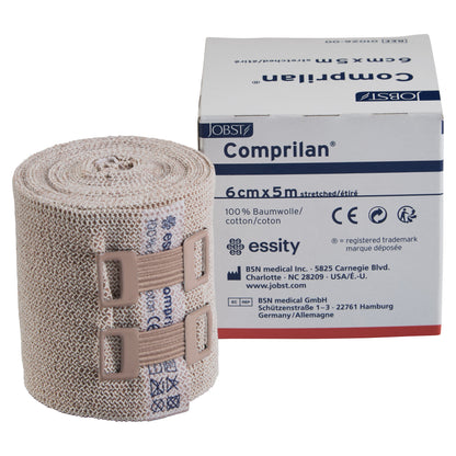 BSN Comprilan Bandage in its packaging next to a rolled bandage with two fasteners, labeled 6cm x 5m and made of 100% cotton.