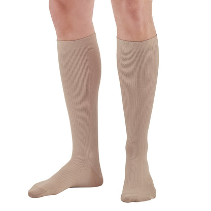 A person wears Ames Walker Knee-Length Microfiber Support Socks in beige, featuring a ribbed texture for added support.