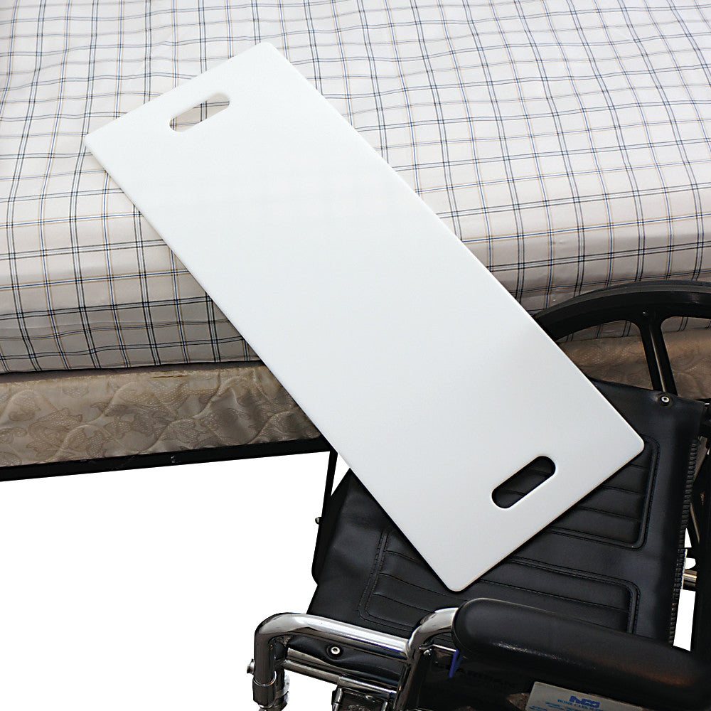 A SafetySure Transfer Board bridging a wheelchair and a bed with a checkered sheet. The board has handgrips for easy handling.