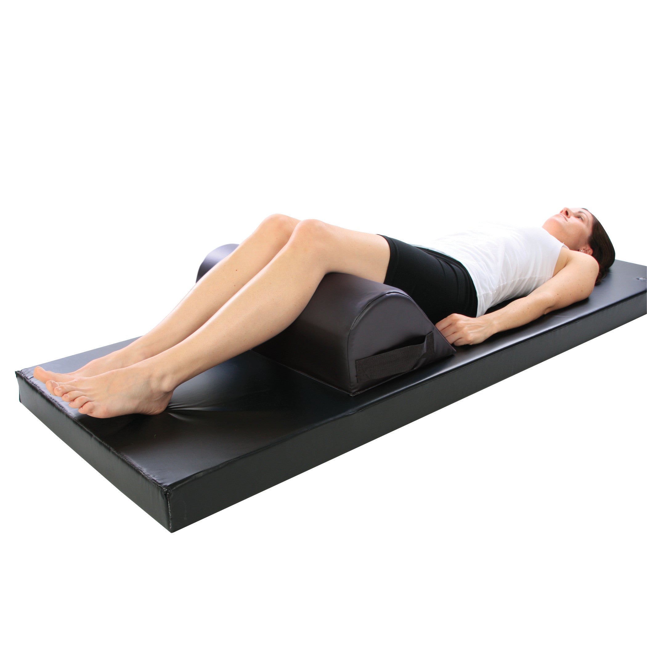 A person lies on a mat with legs resting on the AliMed Vinyl-Covered Standard Knee Bolster for support.