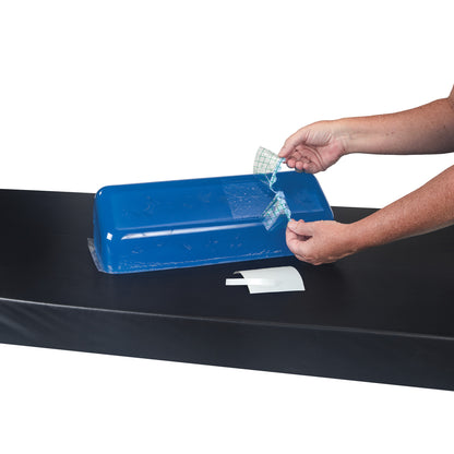 A person uses the AliMed Gel Repair Kit to apply a patch to a blue gel cushion on a black surface.