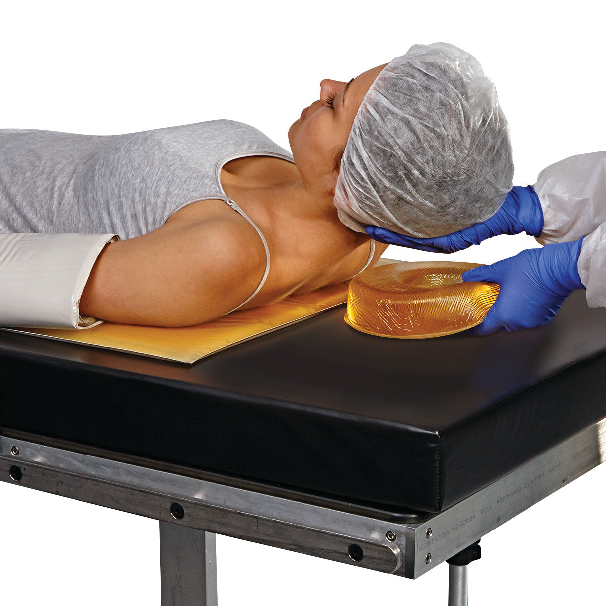 A person is positioned on a medical table, using the AliMed AliGel Basic Positioning Set with a pillow for head support.
