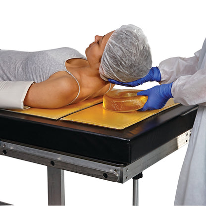 A medical professional positions a patient's head on an AliMed AliGel Select Positioning Set cushion while the patient lies on an exam table.