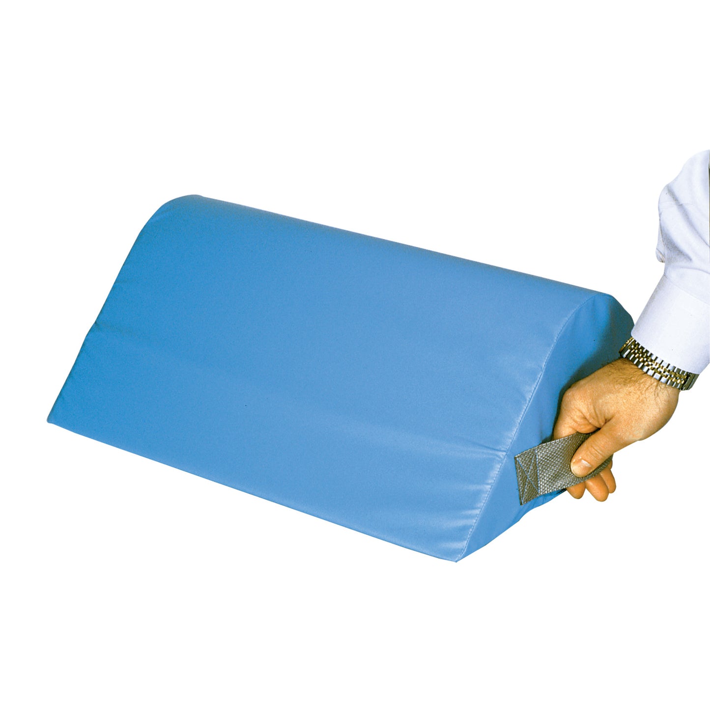 A person holds the AliMed Vinyl-Covered Standard Knee Bolster, a blue, trapezoidal cushion with a handle on the side.