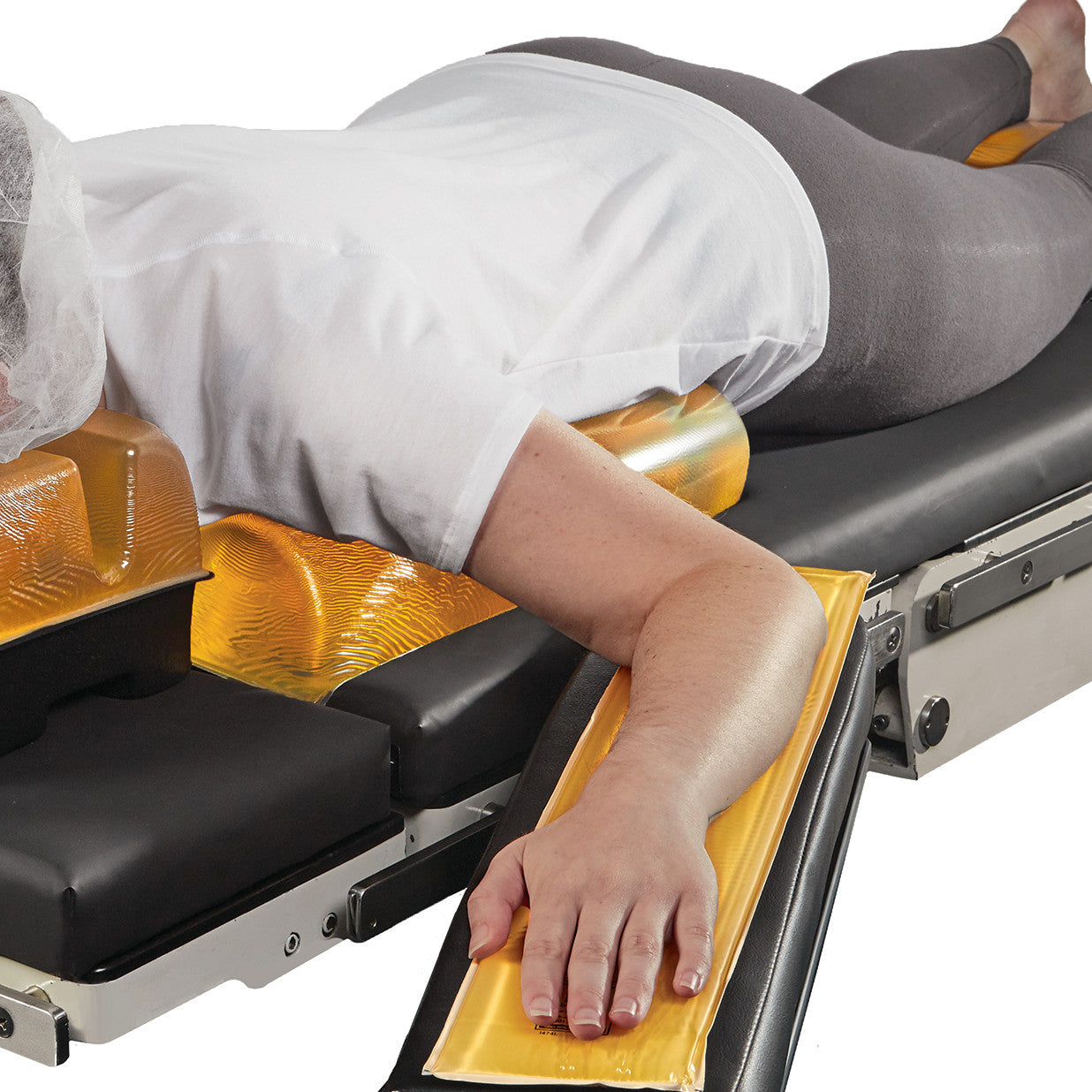 A person lies facedown on a table using AliMed AliGel Chest Roll for support, with other gel pads under the arms and waist.