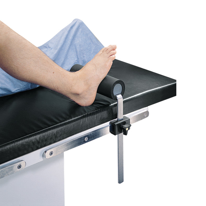 A foot rests on a "Replacement Pad for Allen Total Knee Stabilizer," attached to a black cushioned medical table.