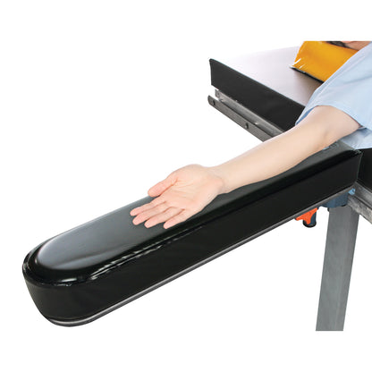 A person's arm rests on the AliMed Gel Composite Armboard Pad, which is black with a soft, cushioned surface, attached to a table.