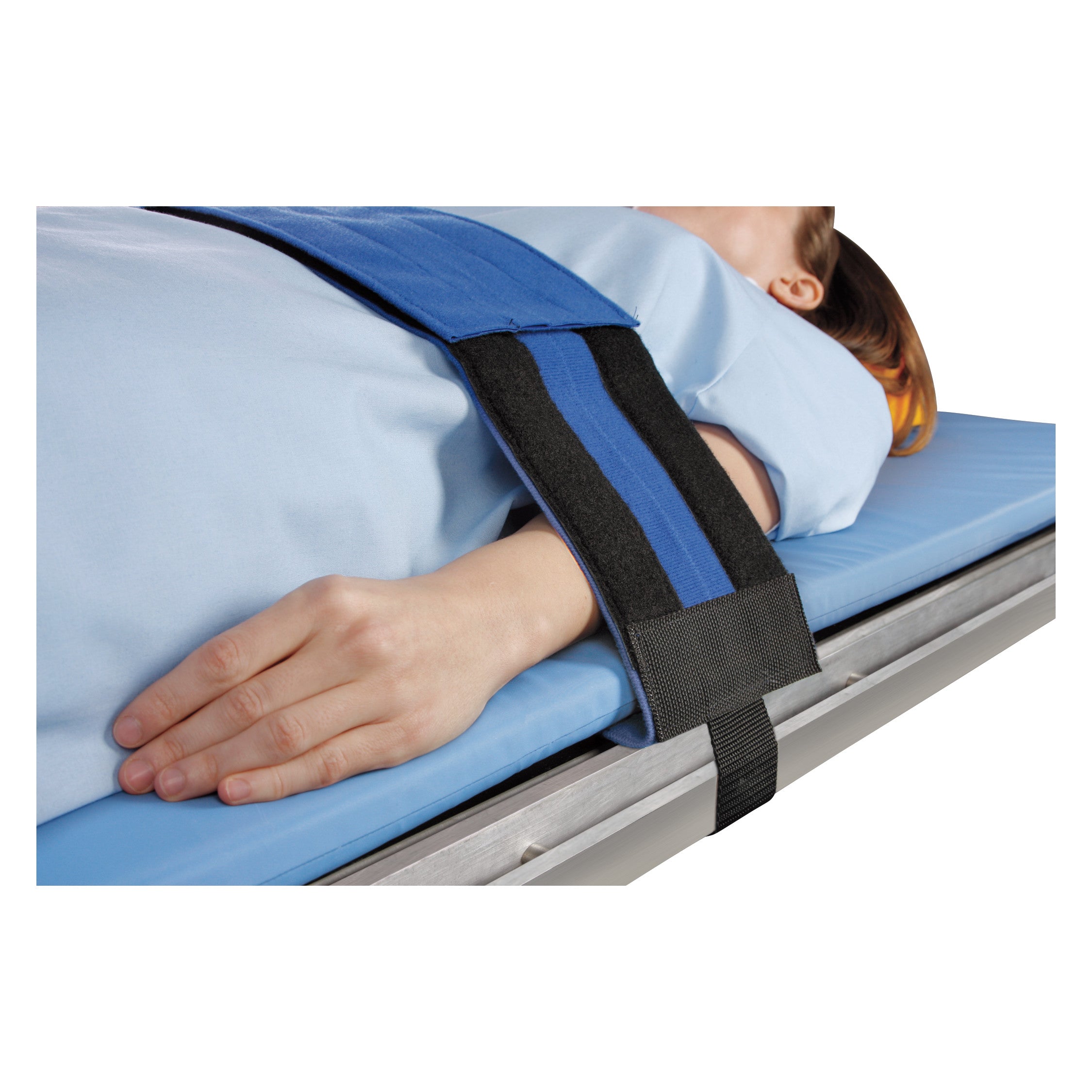 A person is secured with the AliMed Cath Lab Immobilizer, a blue and black strap, while lying on a padded medical table.