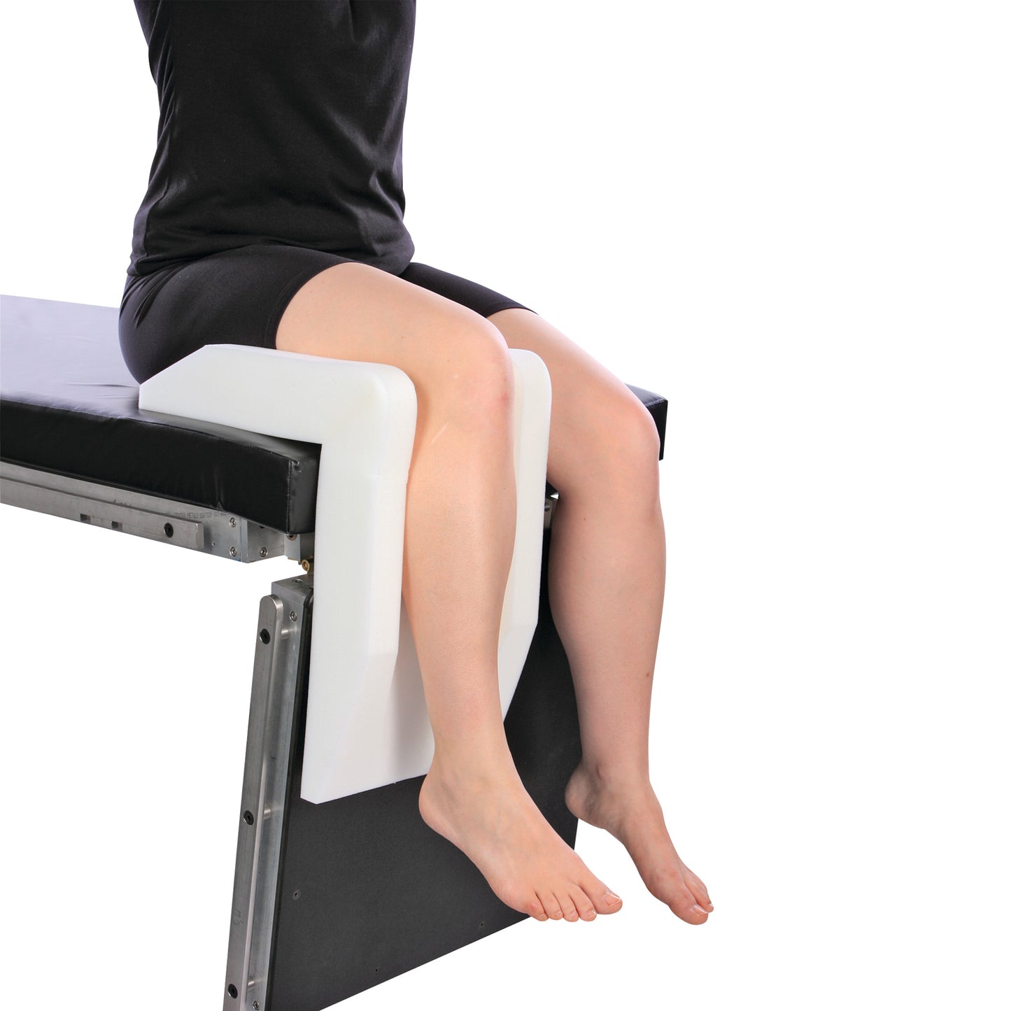 A person sits using the AliMed Arthroscopic Well-Leg Holder, which supports the legs on a cushioned platform attached to a table.