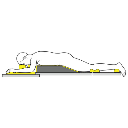 A person is lying face down on an AliMed AliLite Prone Positioning Set, using yellow foam supports for head, chest, pelvis, and feet.