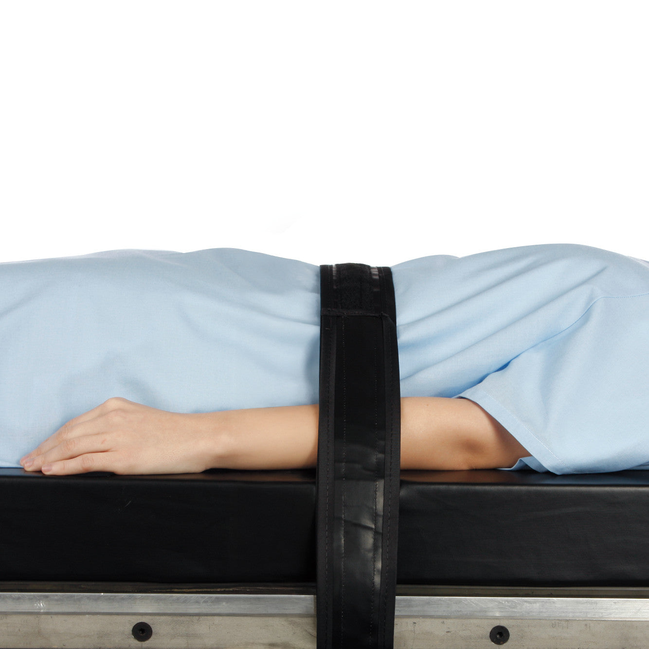 A patient in a light blue gown is secured to an operating table with the AliMed Nonmetallic Operating Room Table Strap across their body.