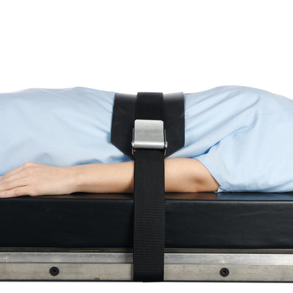 Person lying on a surface secured with AliMed Basic Mid-Panel Straps, featuring a black strap and a silver buckle over the torso.