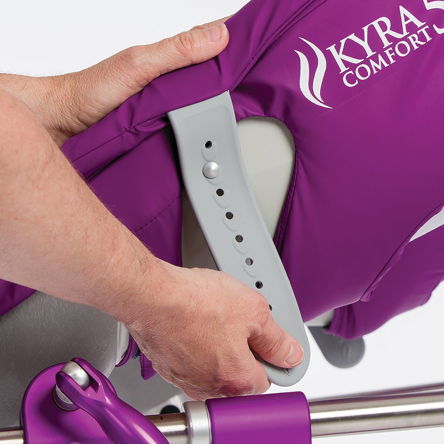 A hand adjusts the KYRA Comfort 350 Lithotomy Stirrup with Secure-Lok Straps, featuring a purple padded cover and adjustable settings.