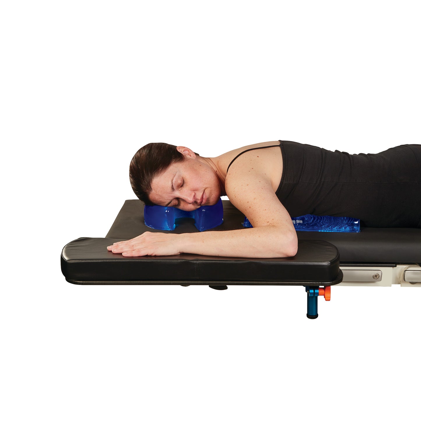 A woman lies face down on a black table, using the AliMed AliBlue Gel Horseshoe Donut for neck support.