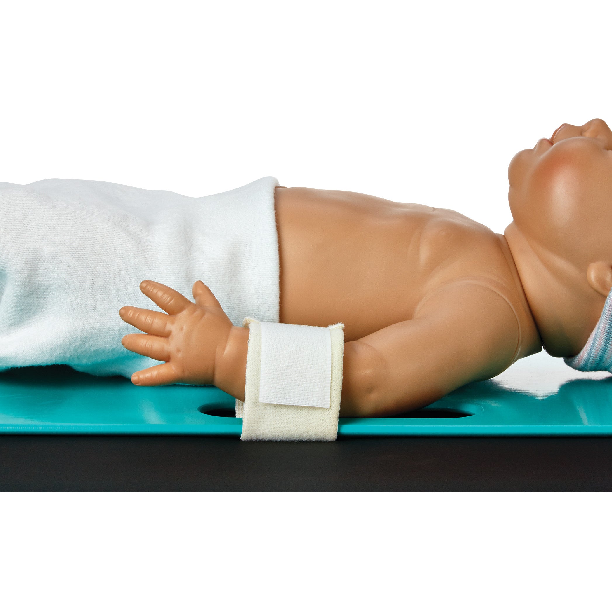 A baby mannequin on its side with an Arista Baby Board Strap around its wrist, demonstrating proper restraint use on a blue board.
