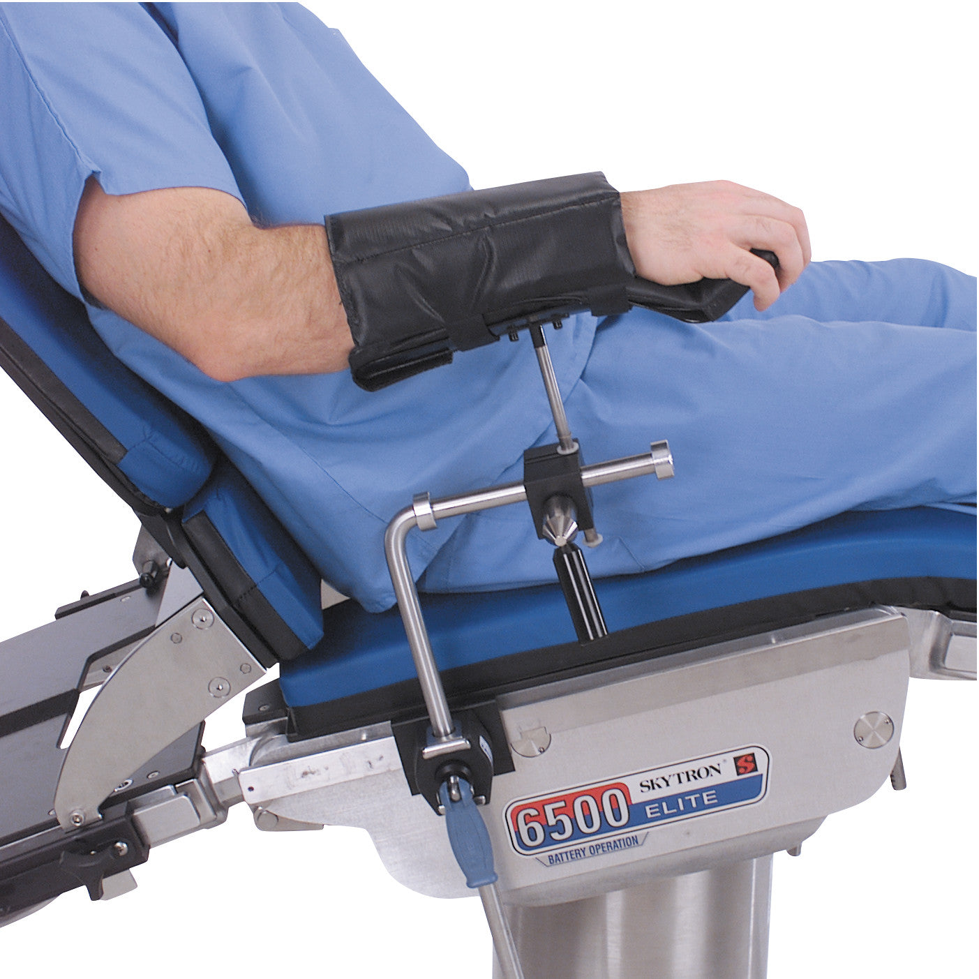 A person in scrubs is seated on a Skytron 6500 Elite table, using a Replacement Pad for Allen Lateral and Prone Arm Support.