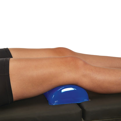 A person's legs rest on a blue AliMed AliBlue Gel Dome Positioner, placed on a black surface.