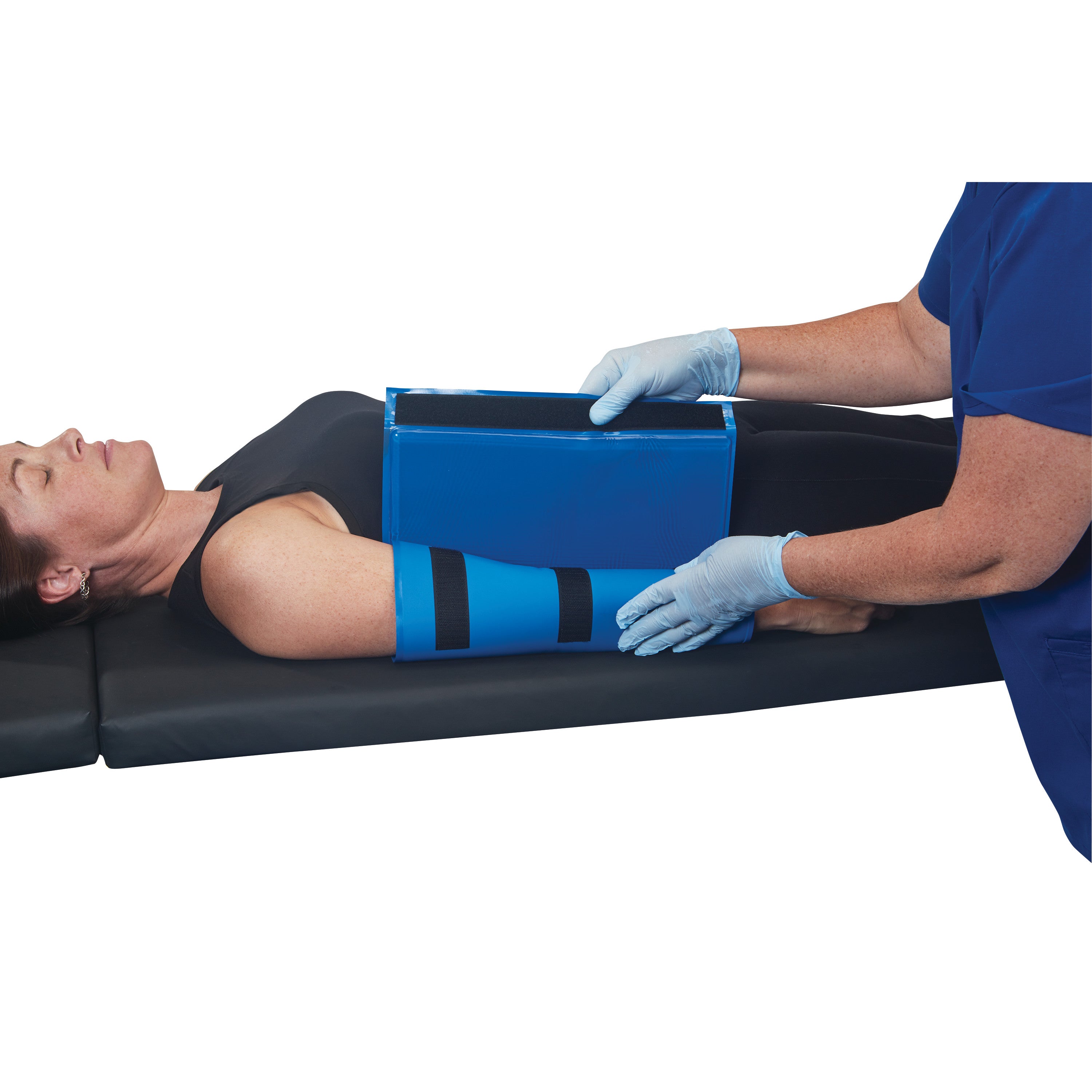 A person lies on a mat with their arm in an AliMed AliBlue Gel Ulnar Forearm Protector. A gloved person adjusts the device.