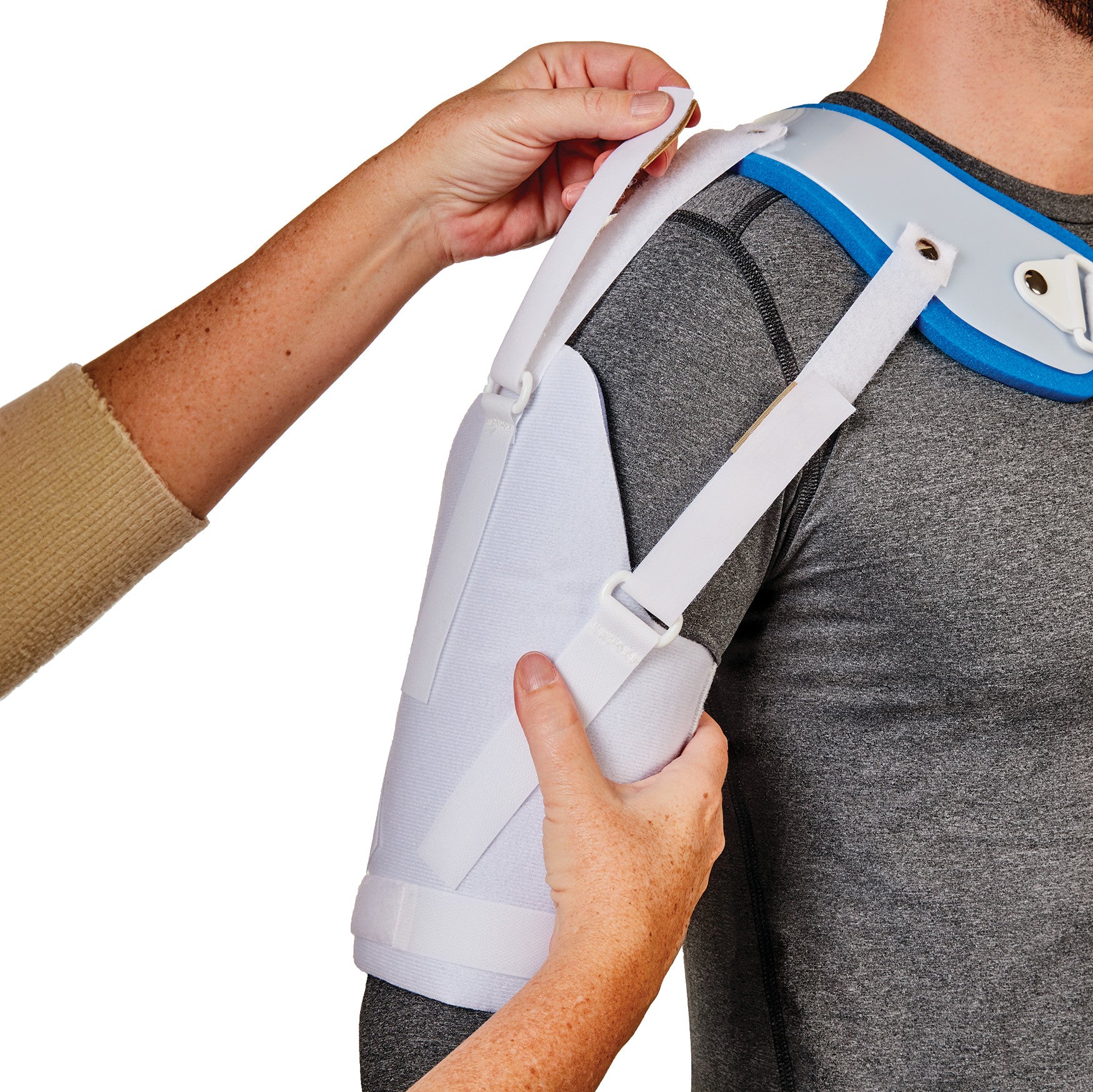 A person assists another in wearing an AliMed Hemi-Shoulder Sling on the right shoulder over a gray long-sleeve shirt.