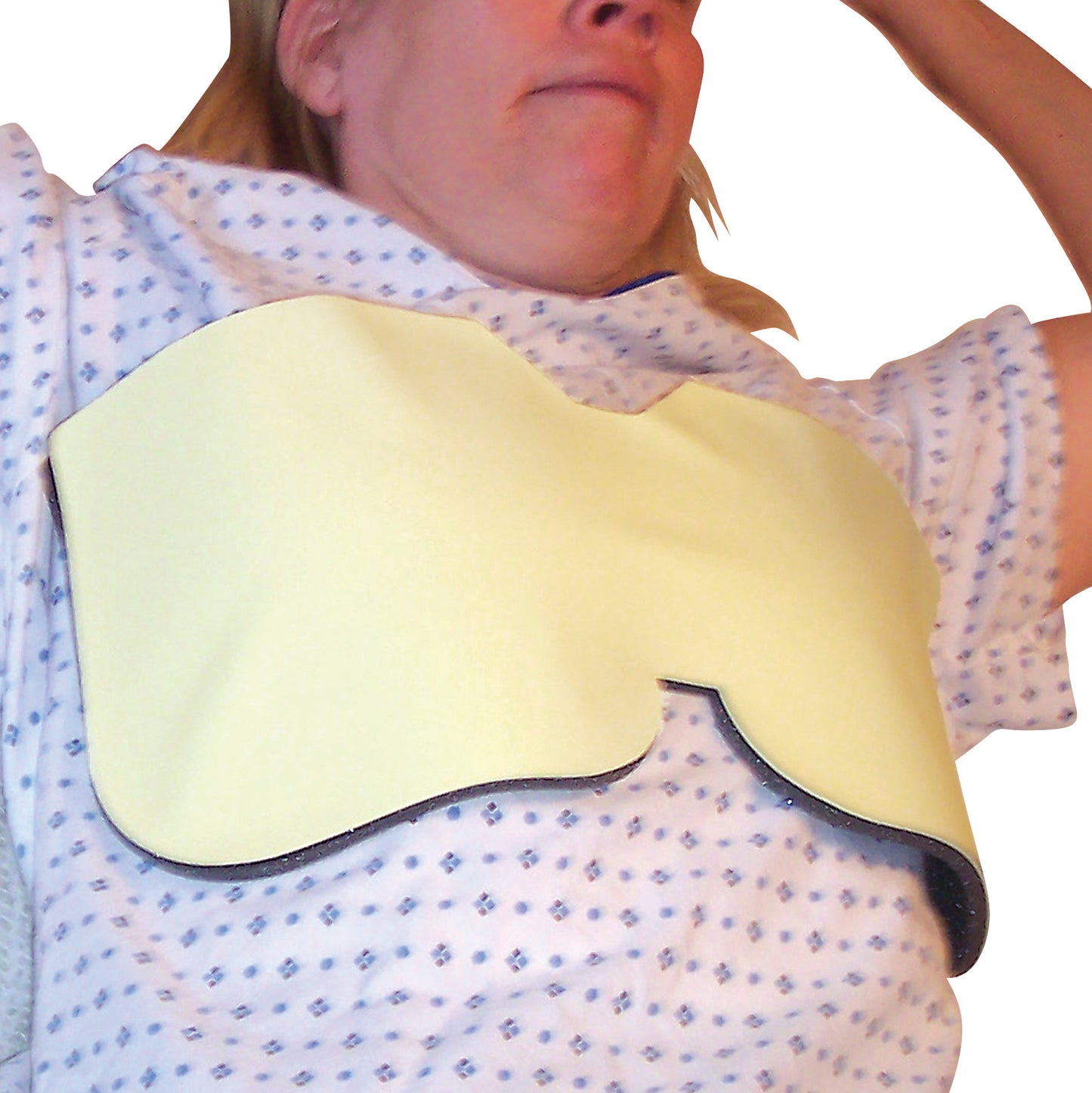 A person wearing an AttenuRad CT Breast Shield, made of a yellow material, over a patterned hospital gown.