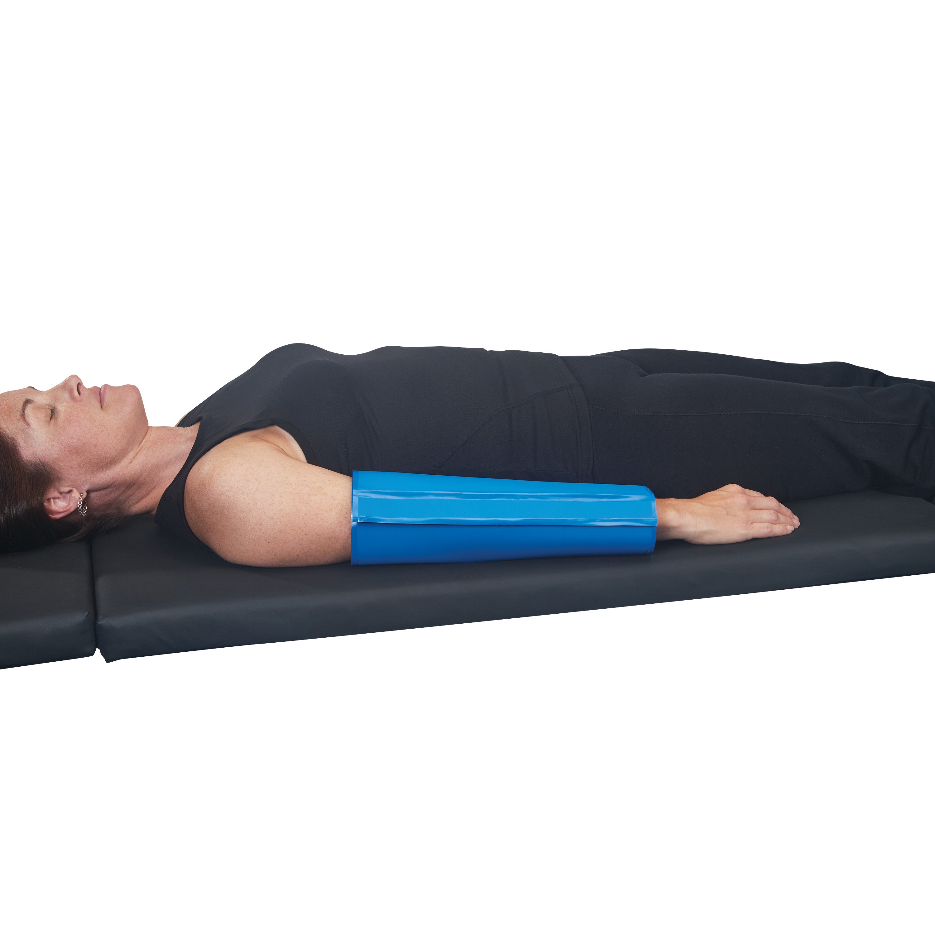 A person lies on a mat with an AliMed AliBlue Gel Ulnar Forearm Protector on their left forearm, wearing black clothing.