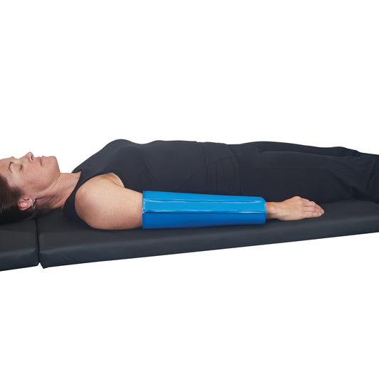 A person lies on a mat with an AliMed AliBlue Gel Ulnar Forearm Protector on their left forearm, wearing black clothing.