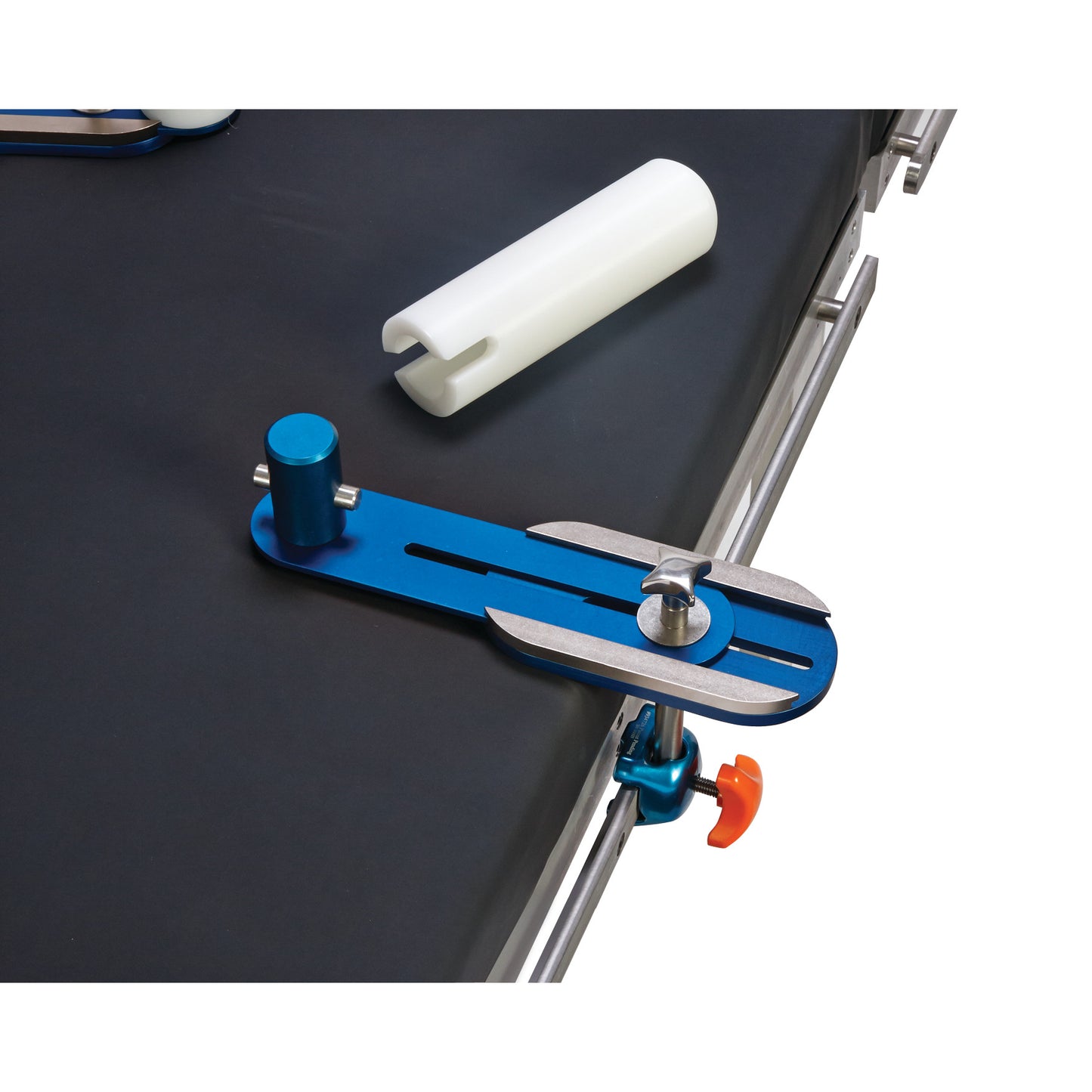 The AliMed Lateral Positioner Set with a blue and silver clamp and a white cylindrical accessory on a dark surface.