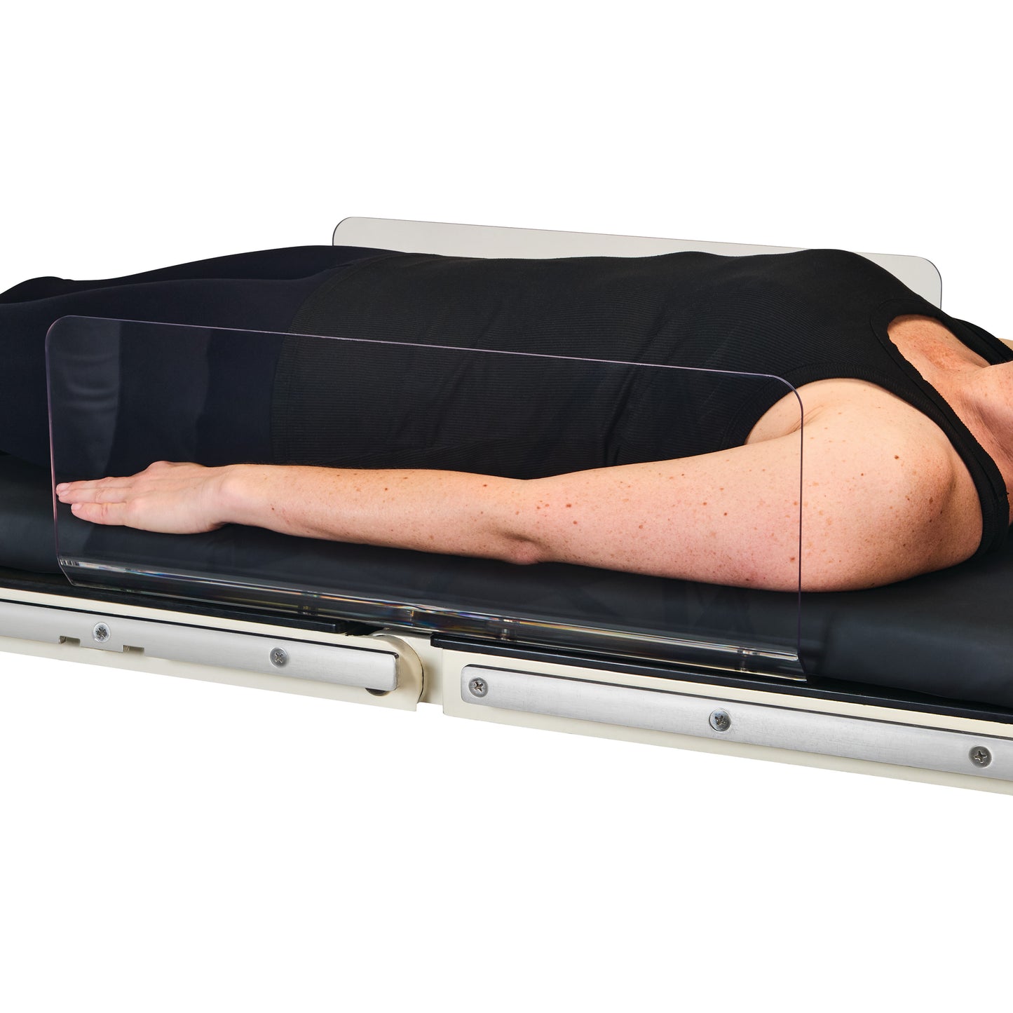 A person lies on a table with an AliMed Straight Toboggan Arm/Leg Guard protecting the arm, shown by a clear plastic barrier.
