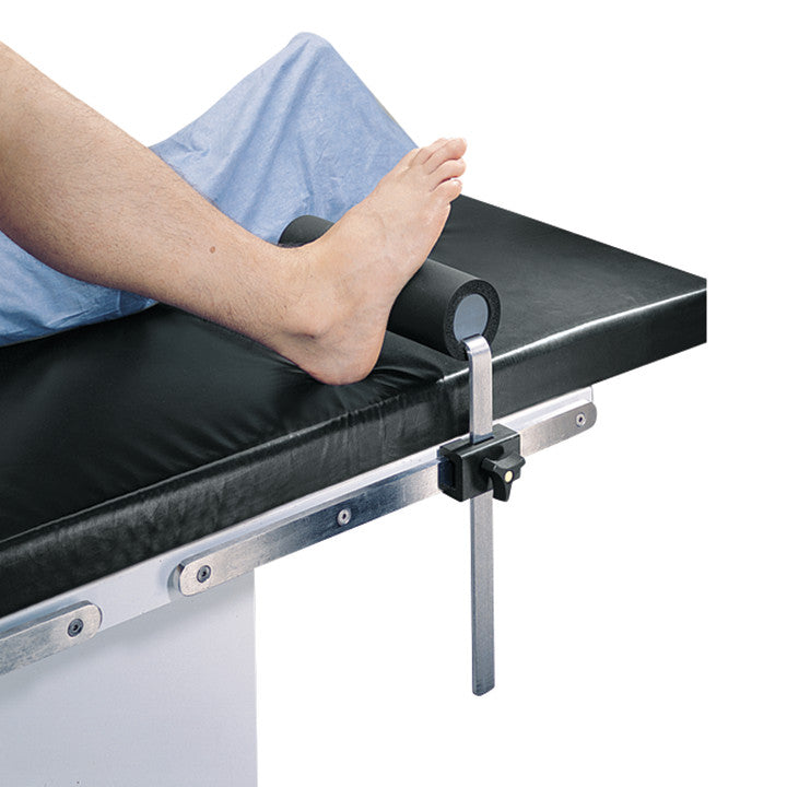 A person uses the Allen Total Knee Stabilizer to support their raised leg on a medical table with a black cushion.