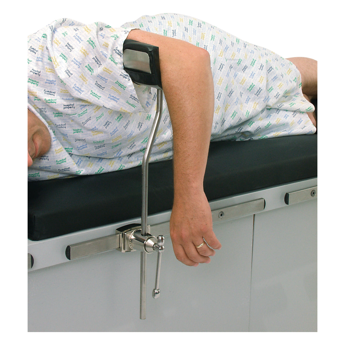 A person is lying on an examination table using the AliMed Elbow Arthroscopy Positioner. The device supports the elbow in place.