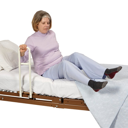 A person uses the Transfer Handle Hospital Model for Pan-Style Beds, gripping the handle to assist in sitting on the bed.