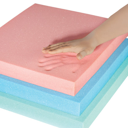 A hand presses into a pink AliMed T-Foam Uncovered Wheelchair Cushion, leaving an imprint. Blue and green foam layers are beneath.