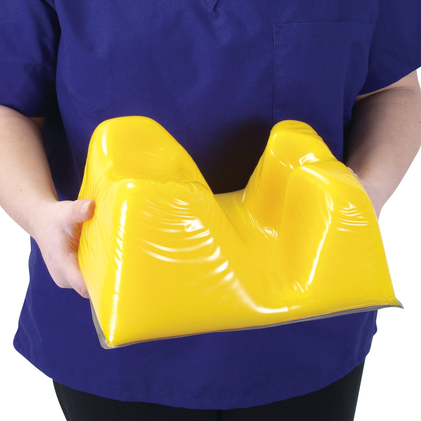 Person holding a yellow AliMed AliLite Prone Headrest, designed to support the head during prone positioning.