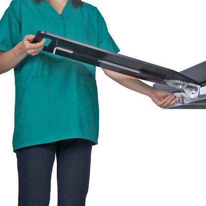 A person adjusts an AliMed Pivoting Armboard, wearing green medical scrubs. The armboard is partially extended.