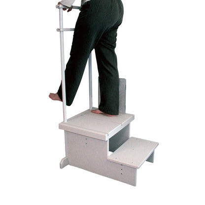 A person stands on the Two-Step Positioning Platform for CR Systems and DR Systems, gripping a vertical handle for support.