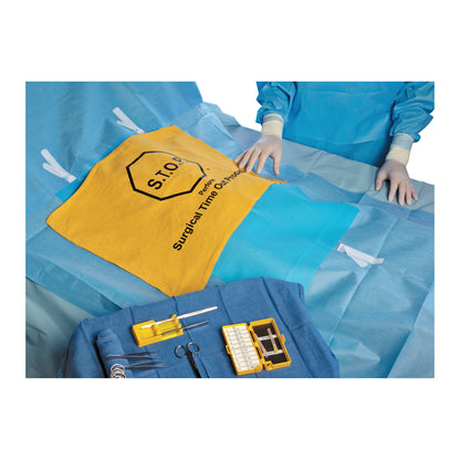 A surgical setup with a S.T.O.P. Safety Flag on the table, surrounded by medical tools and a person in blue surgical attire.