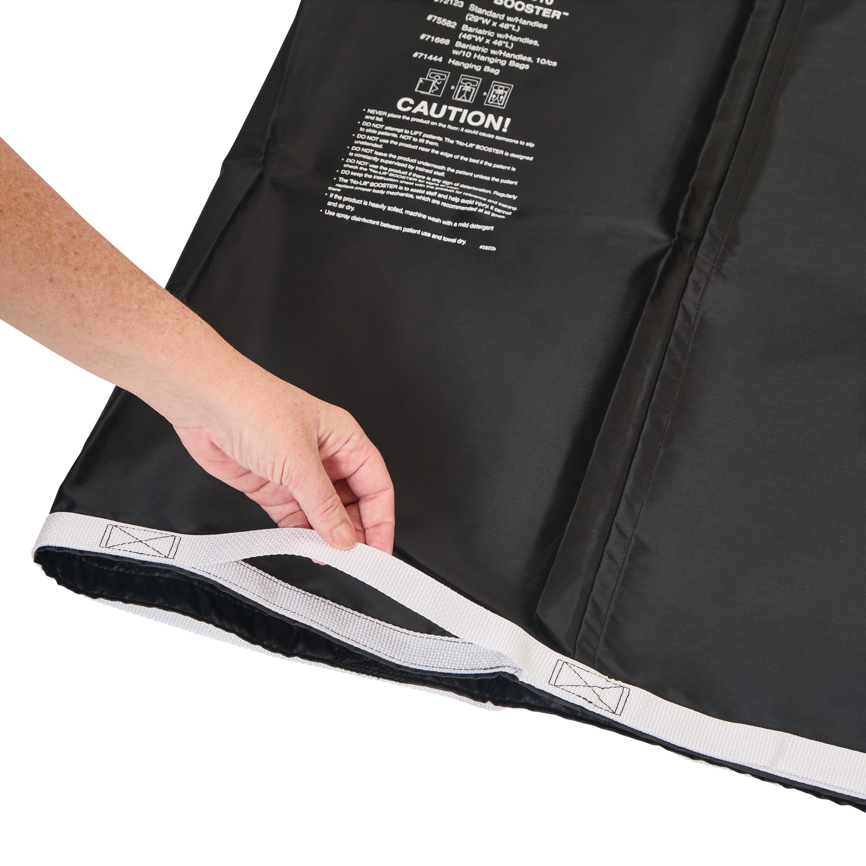 A hand holds the edge of an AliMed No-Lift BOOSTER, showing its black fabric and white strap with warning text printed on it.