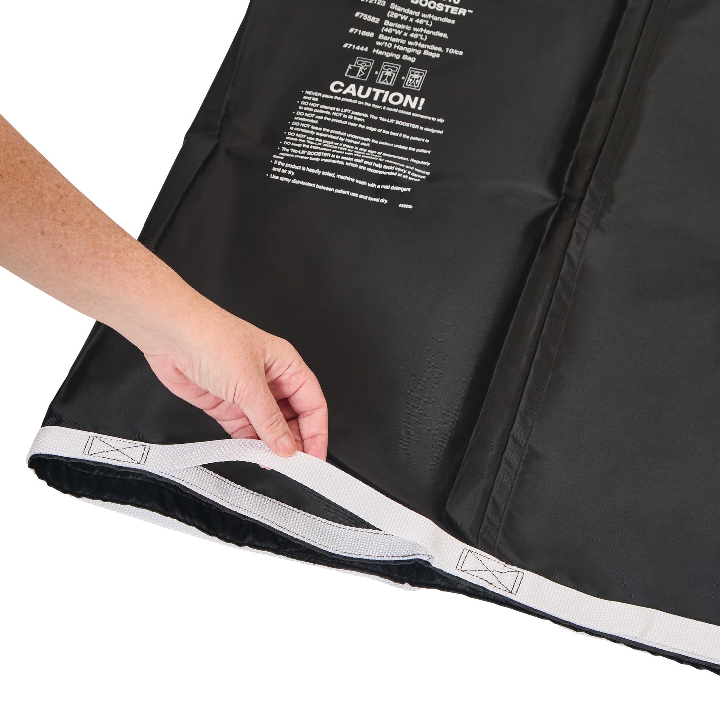 A hand holds the edge of an AliMed No-Lift BOOSTER, showing its black fabric and white strap with warning text printed on it.