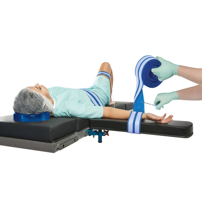 A patient is secured on a medical table using the AliMed AliStrap Positioning Strap, with a person adjusting the blue strap.