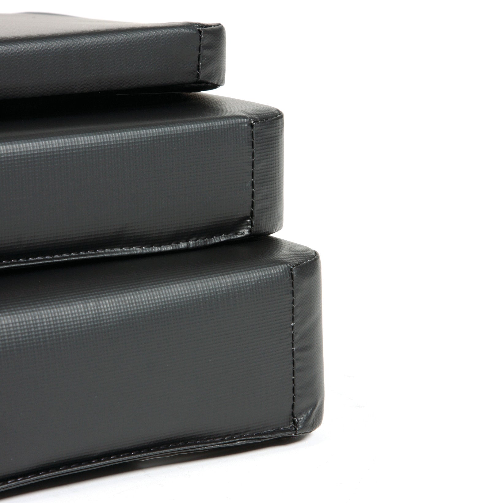 Close-up of stacked black AliMed Standard Armboard Pads, showing their textured surface and stitching.