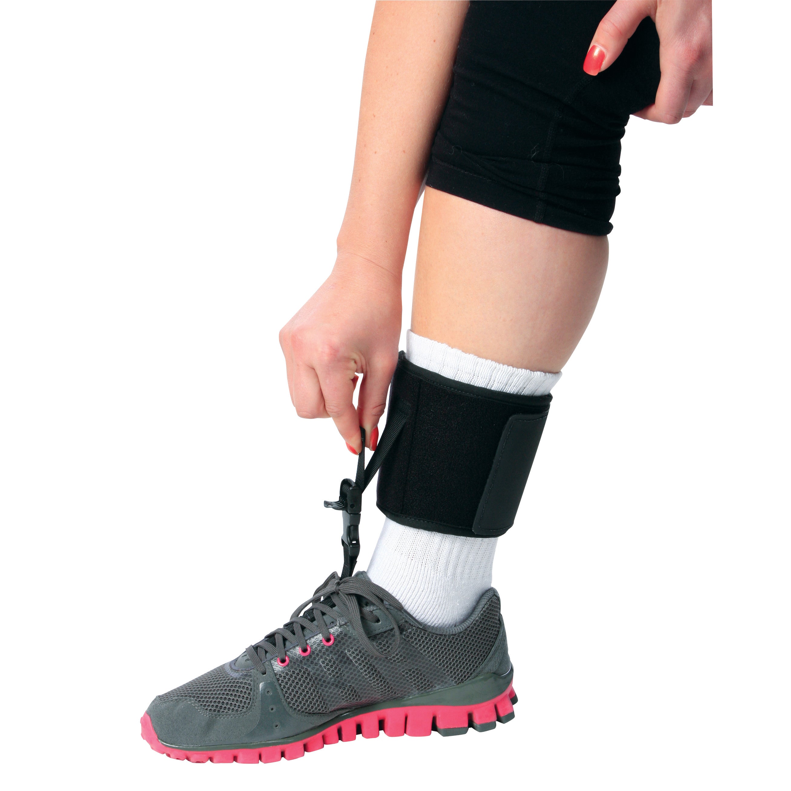 A person adjusts the AliMed FREEDOM Adjustable Footdrop Brace on their leg. They wear a gray sneaker with pink accents.