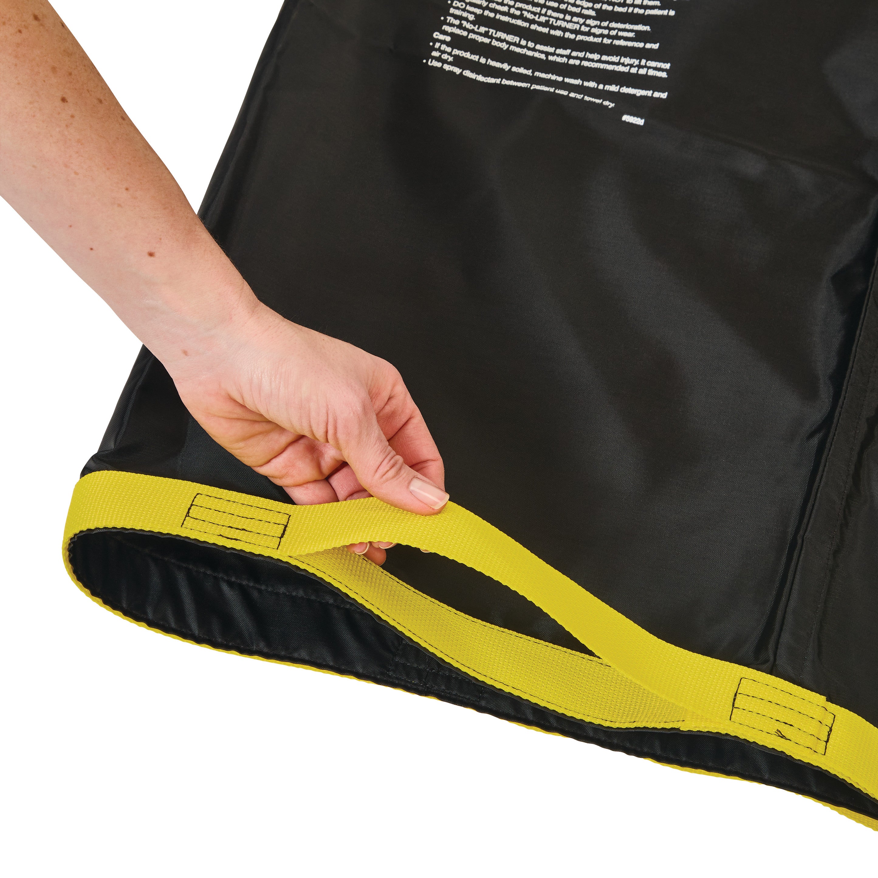 A hand holds a yellow strap of the AliMed No-Lift TURNER, a black patient transfer aid with visible instructions on the surface.