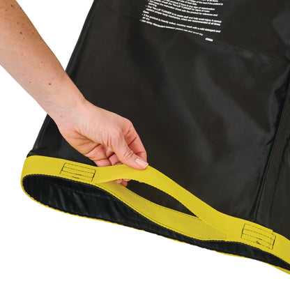 A hand holds a yellow strap of the AliMed No-Lift TURNER, a black patient transfer aid with visible instructions on the surface.