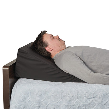 A person lies on the AliMed Bariatric Anti-Reflux Elevating Bed Wedge, covered with a light quilt.