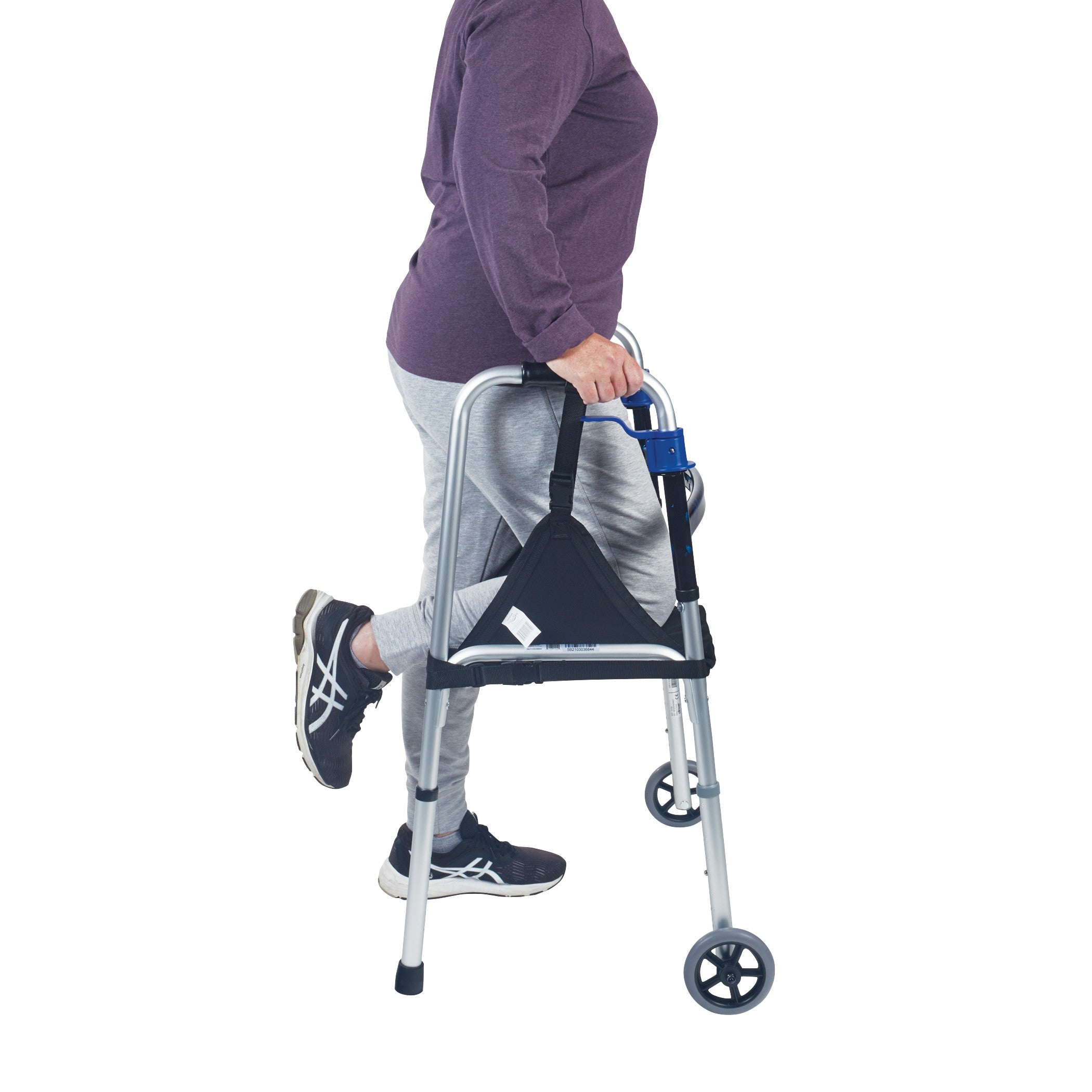 A person using a walker with their knee supported by the SafetySure The Knee Sling, wearing a purple top, gray pants, and black sneakers.