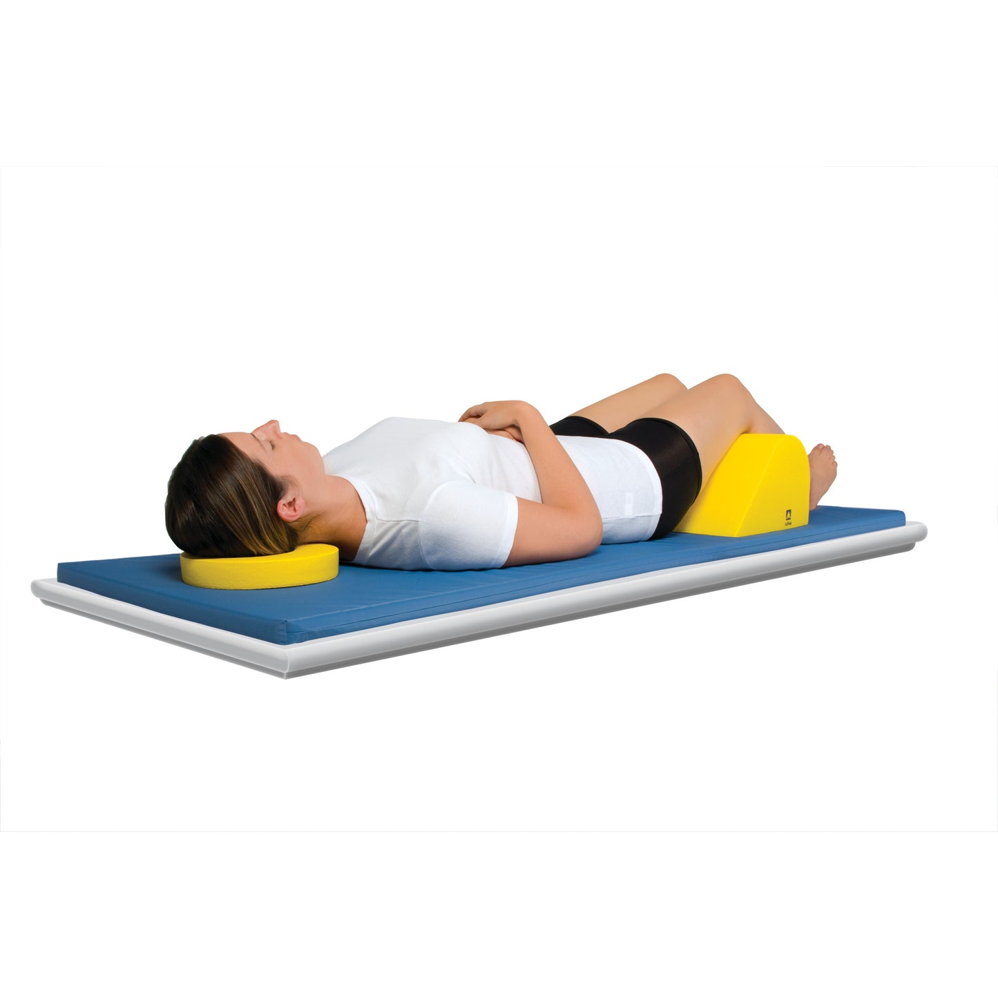 A person lies on a blue mat using an AliMed Protecta-Coat Head Donut for head support and a yellow wedge under the knees.